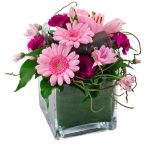 Mixed pink flowers in glass cube